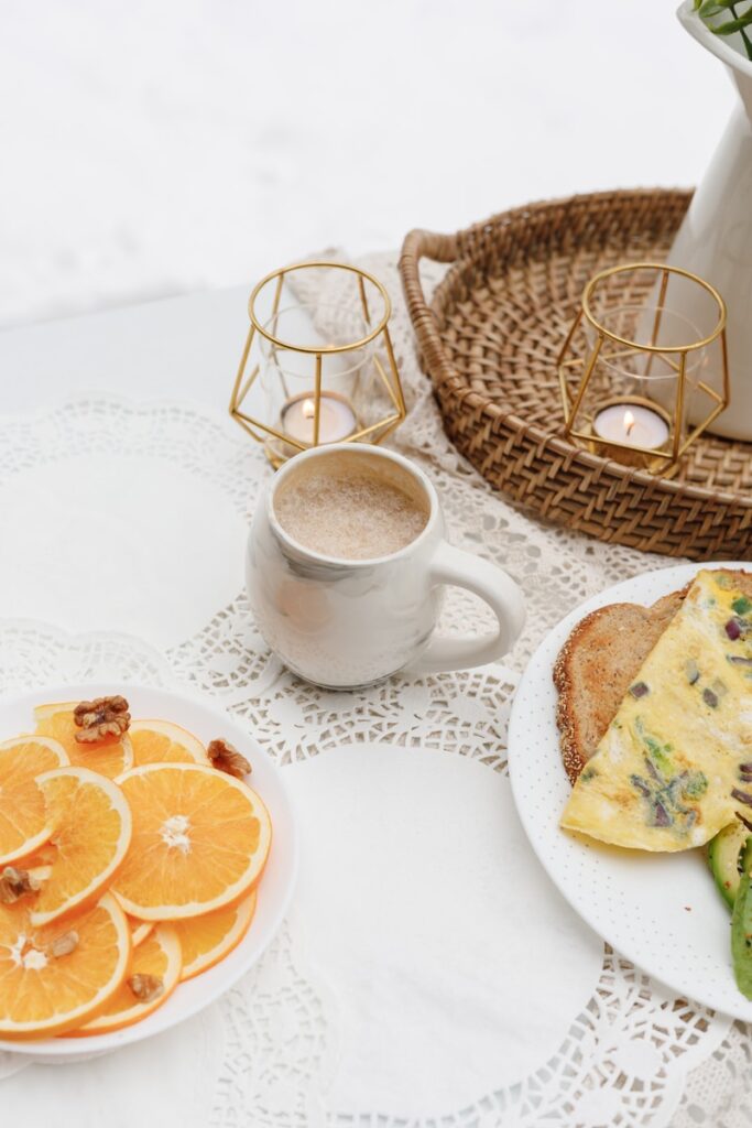 white ceramic mug with coffee beside bread on white ceramic plate