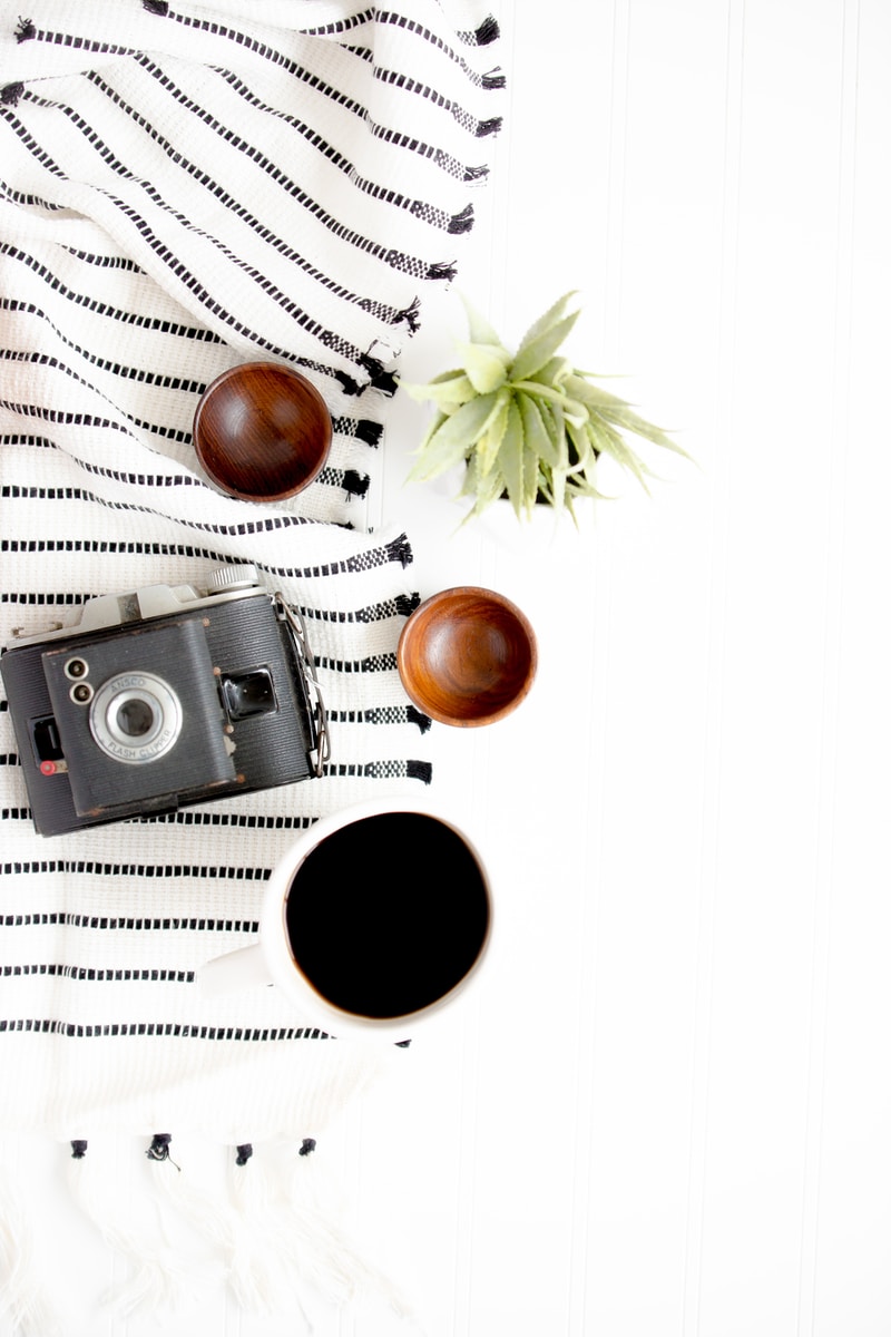 black and gray camera beside on brown wooden bowls