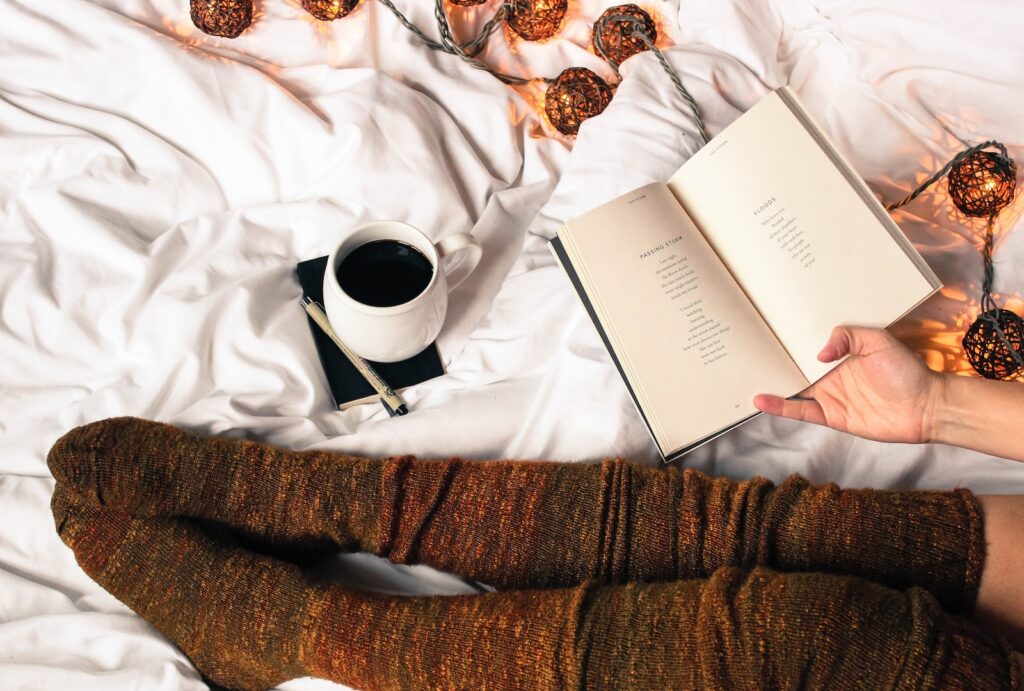 mug of black coffee beside person's feet wearing brown stockigns